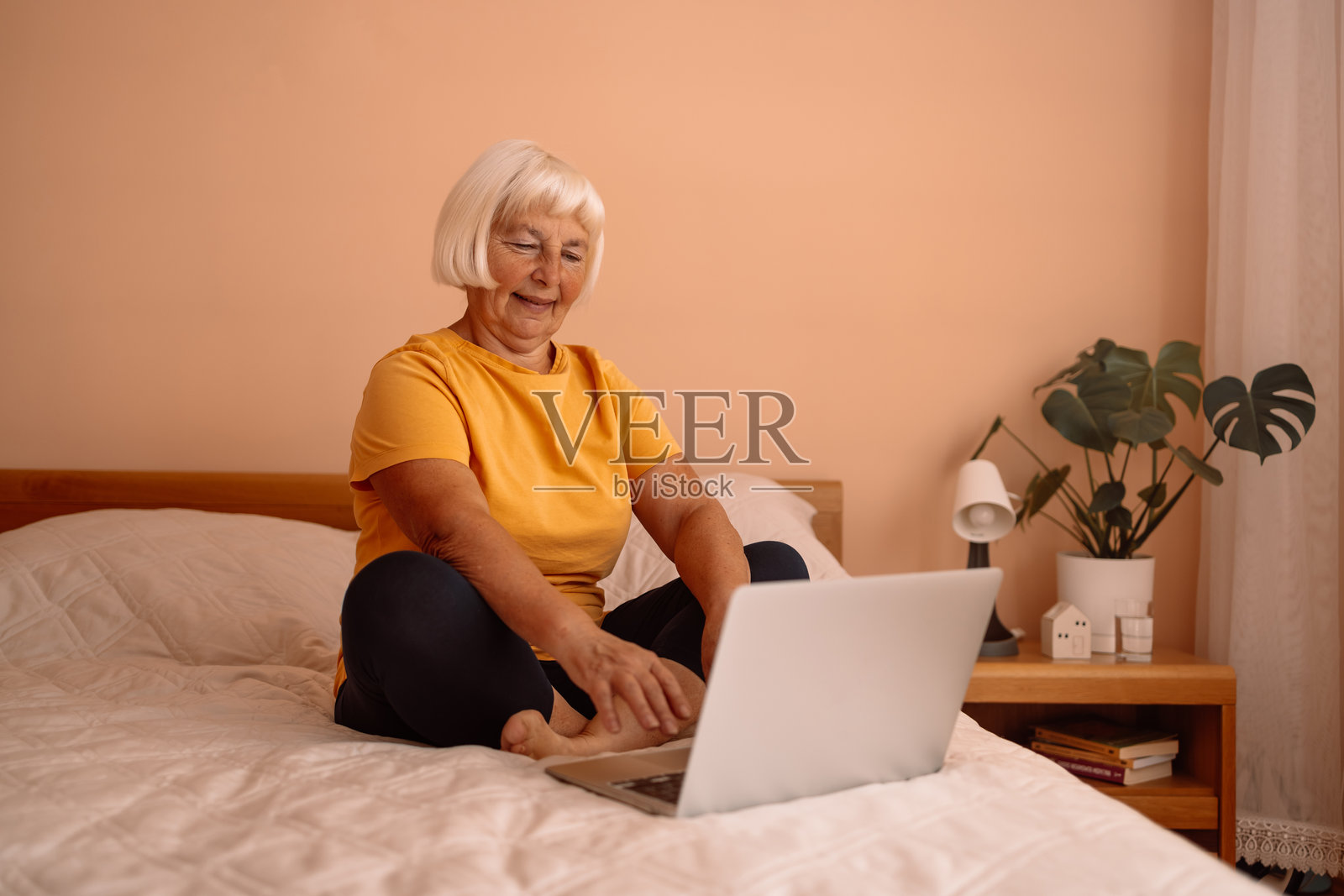 老年女性在公寓的床上使用笔记本电脑进行在线购物照片摄影图片