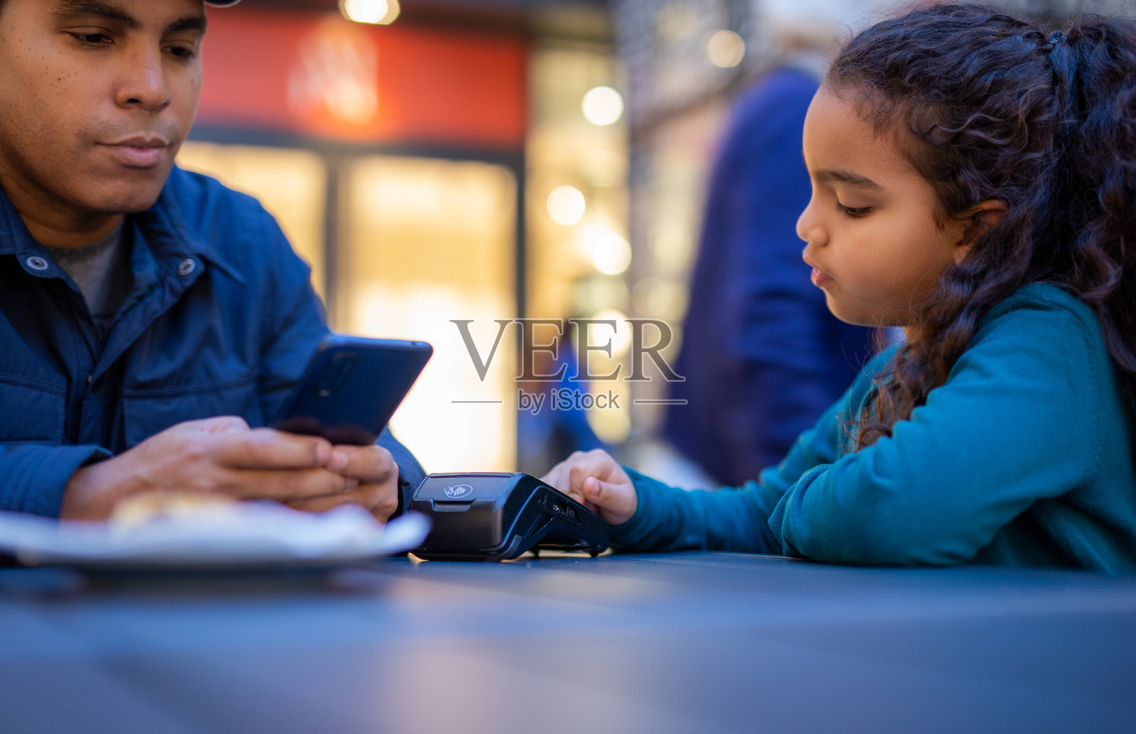 父亲和女儿在商场美食广场使用智能手机进行无接触支付照片摄影图片