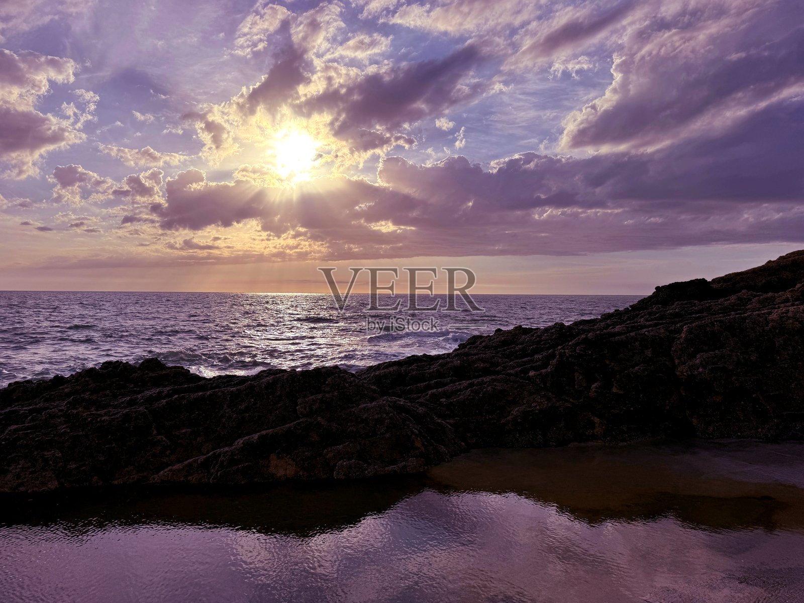 日落天空、平静的海洋和岩石照片摄影图片