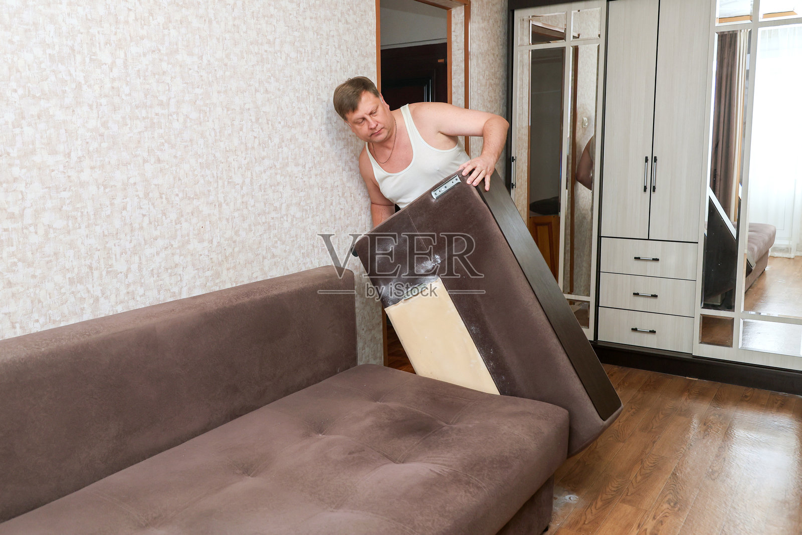 一名男子正在拆解沙发,移除侧背以进行灭虫处理。照片摄影图片