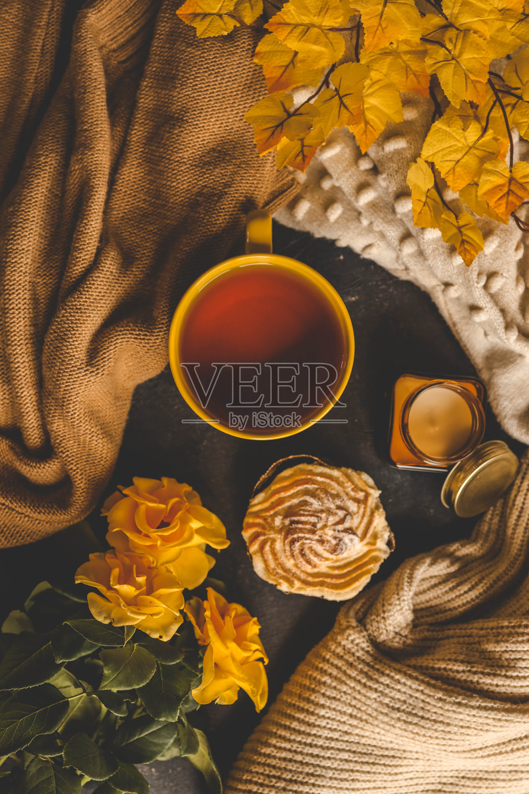 温馨的秋季场景,配有茶、糕点、黄色玫瑰和温暖的针织毛衣照片摄影图片