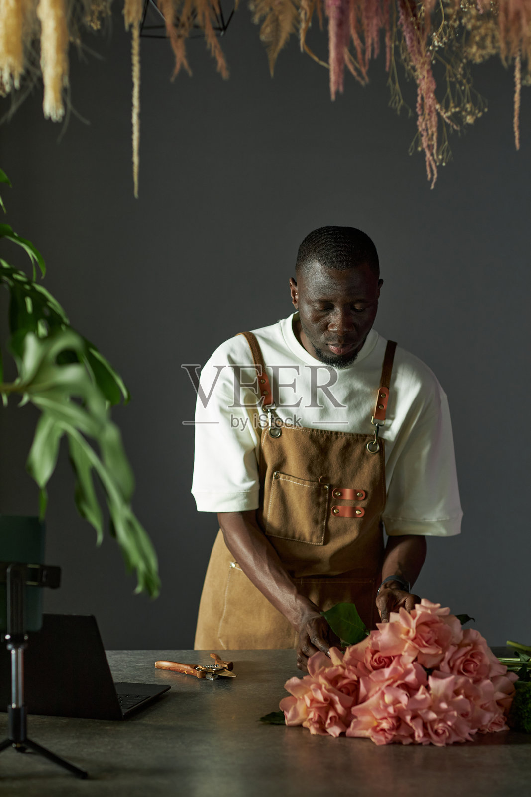 男性花店老板正在制作玫瑰花束并拍摄过程照片摄影图片