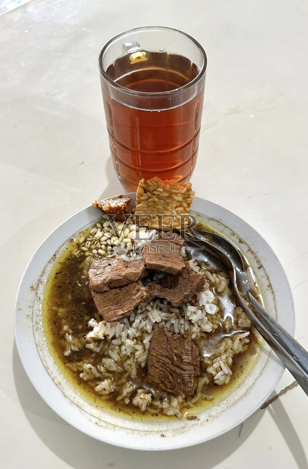 印尼黑牛肉汤(Rawon)盛在瓷碗中,配有卷心菜、辣椒沙司和咸蛋。非常适合食谱、文章或任何烹饪内容。照片摄影图片