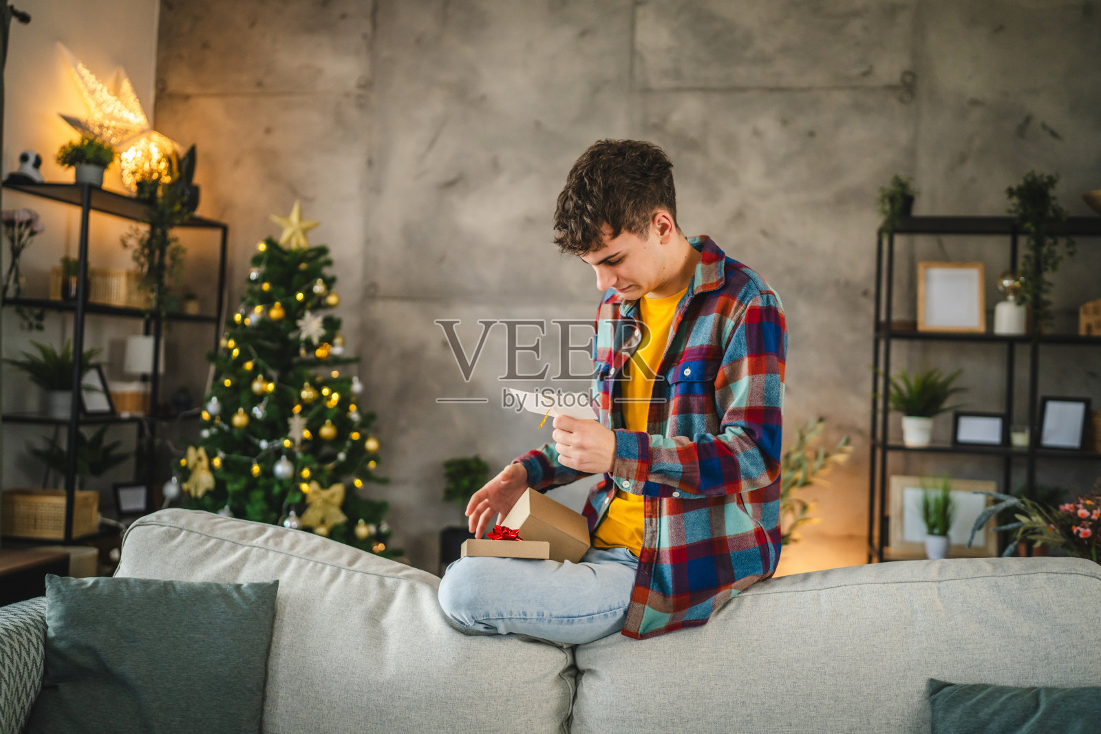 成年男子从圣诞礼物盒中阅读亲密朋友的贺卡照片摄影图片