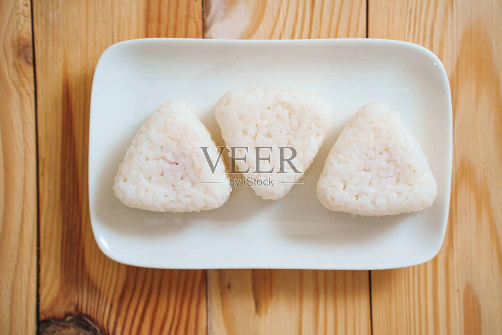 白盘上旋转着米饭制作的饭团。照片摄影图片