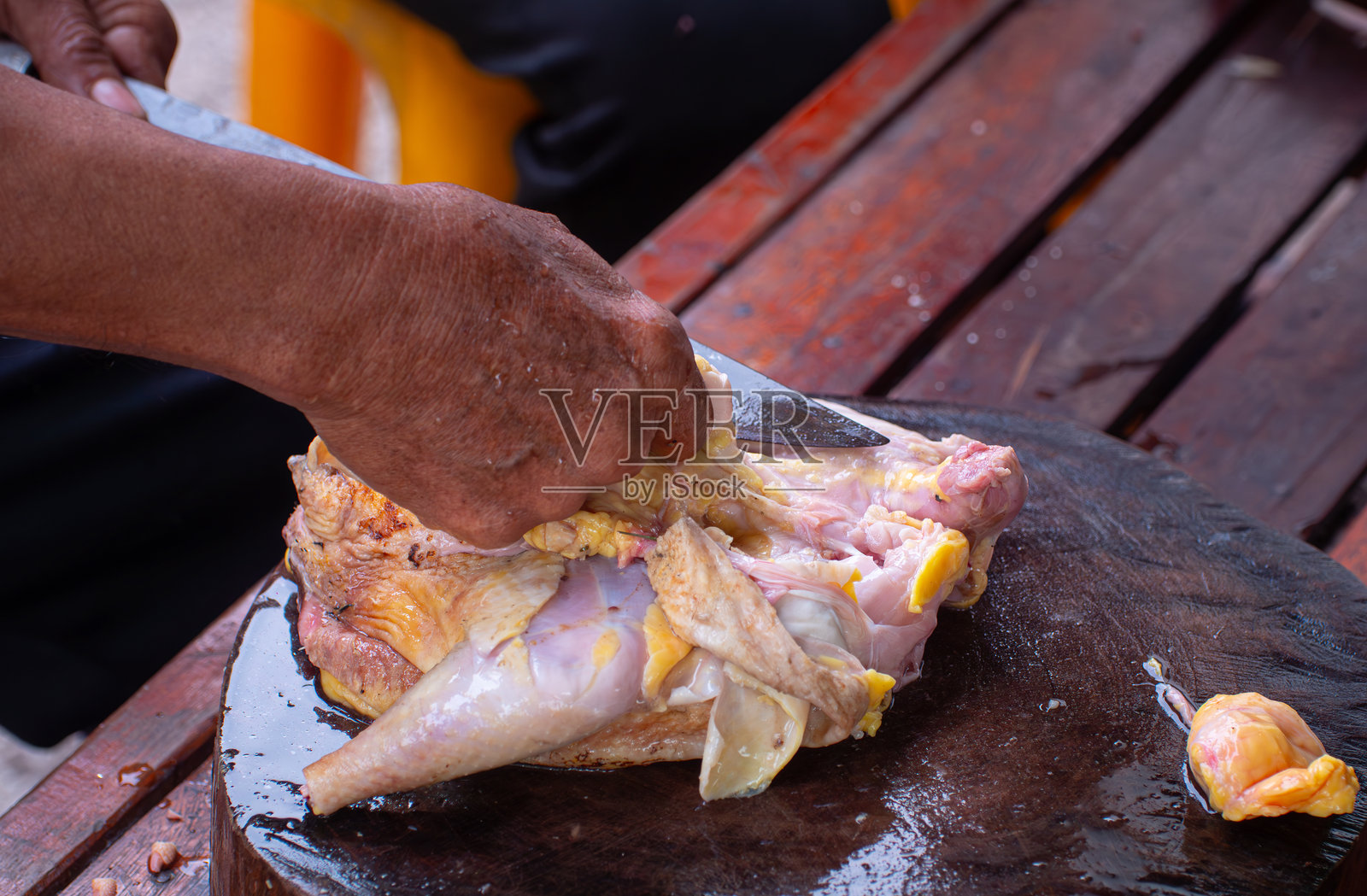 用手在乡村风格下切割或切片生鸡肉。准备烹饪的食材。使用刀具和砧板切割生肉。照片摄影图片
