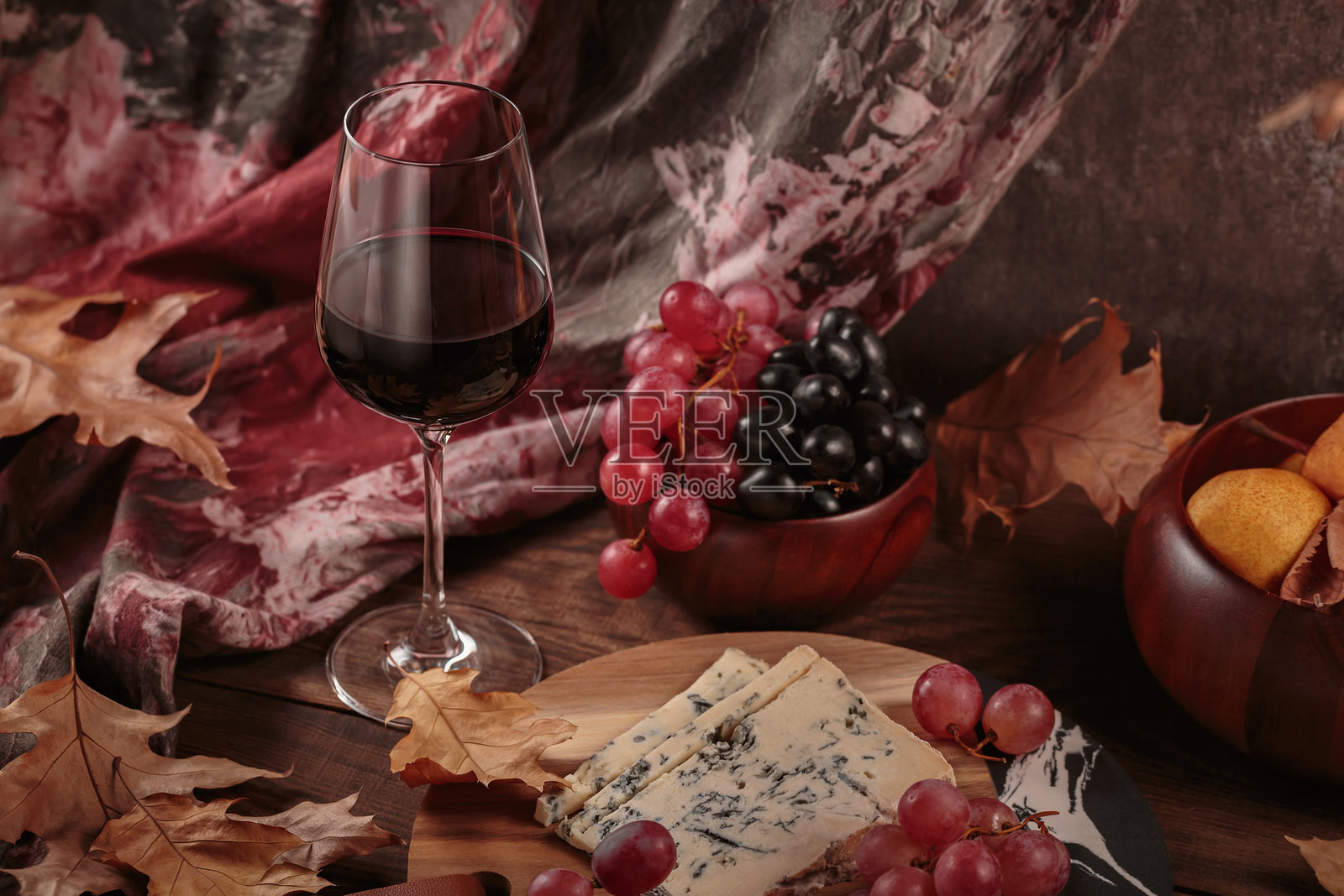 秋季野餐,配有葡萄酒和奶酪拼盘、水果和干枯的树叶照片摄影图片