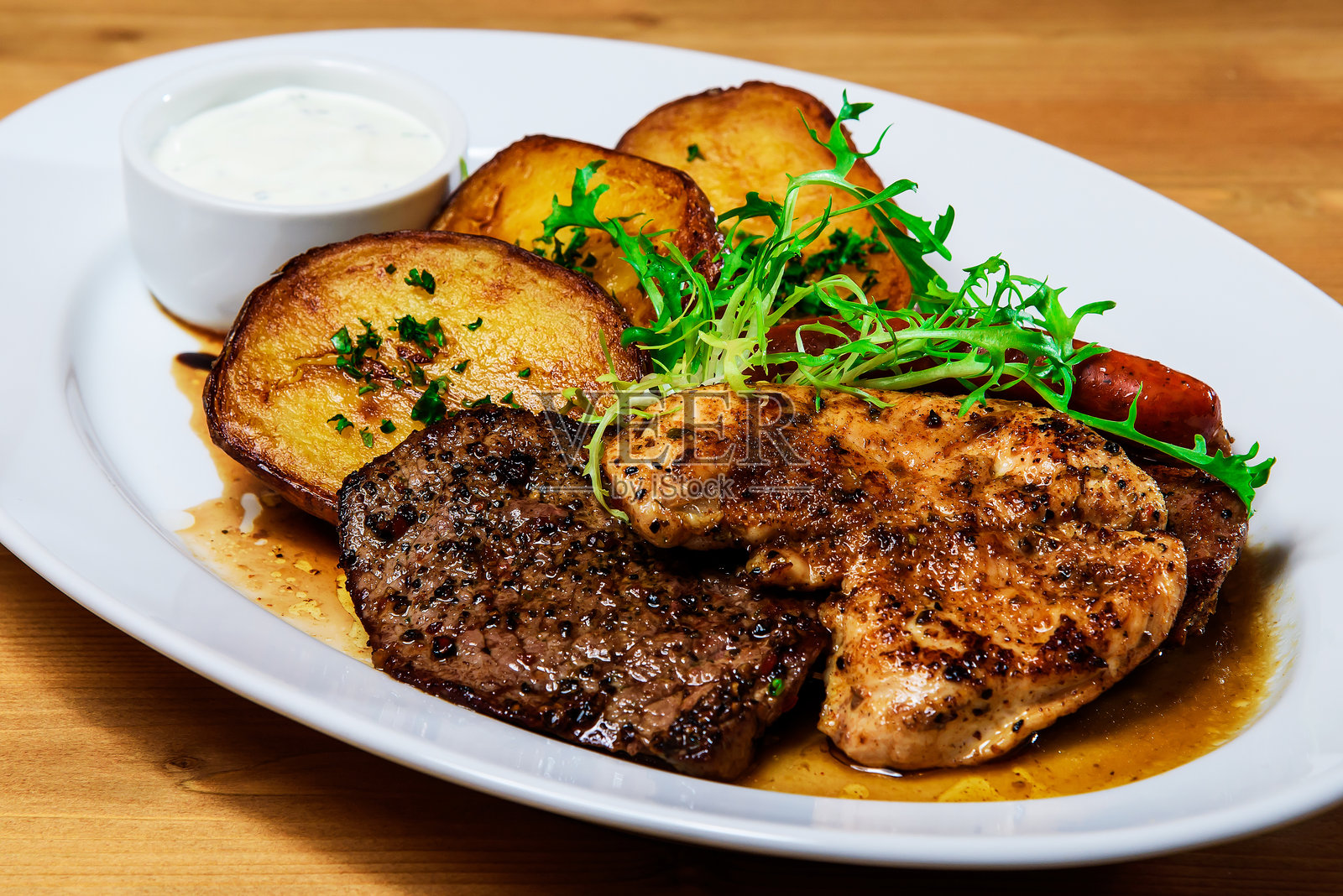 白盘上的烤肉、烤土豆和酱汁照片摄影图片