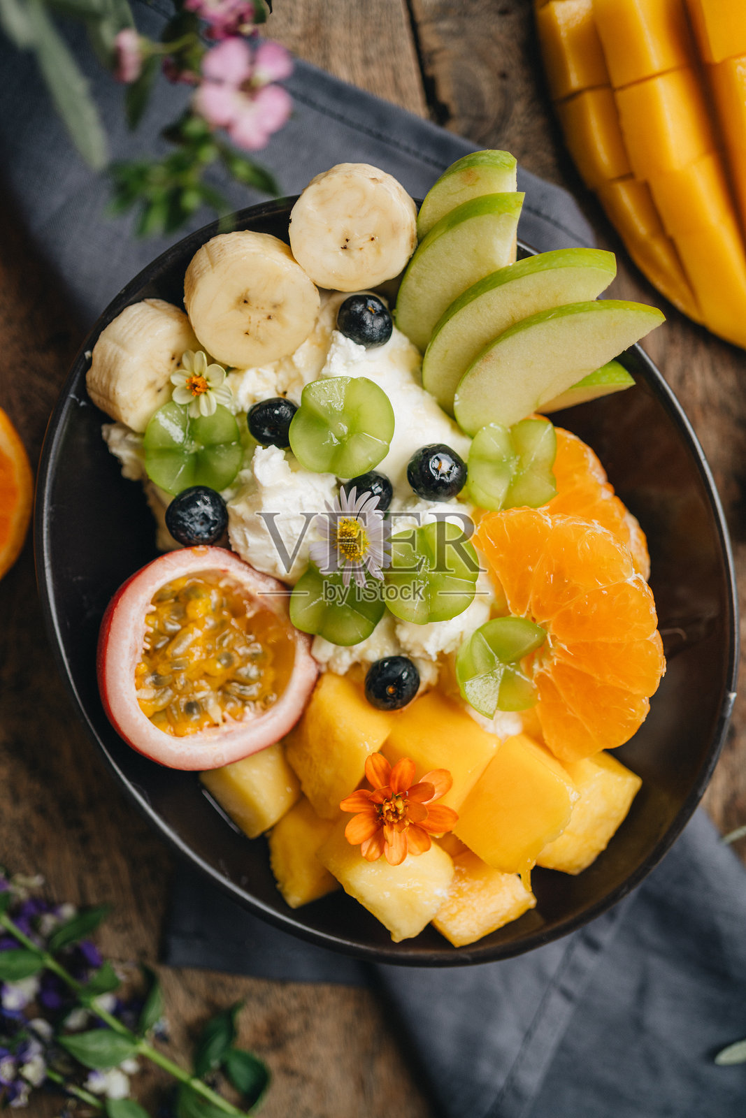 高角度视图的果昔碗,顶部放有新鲜水果,摆放在桌子上的盘子里照片摄影图片