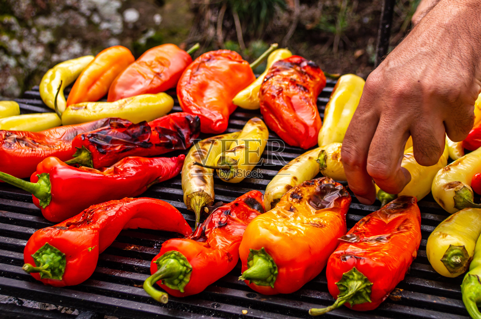 烤架上的蔬菜。男人的手在滚动。辣椒粉。照片摄影图片