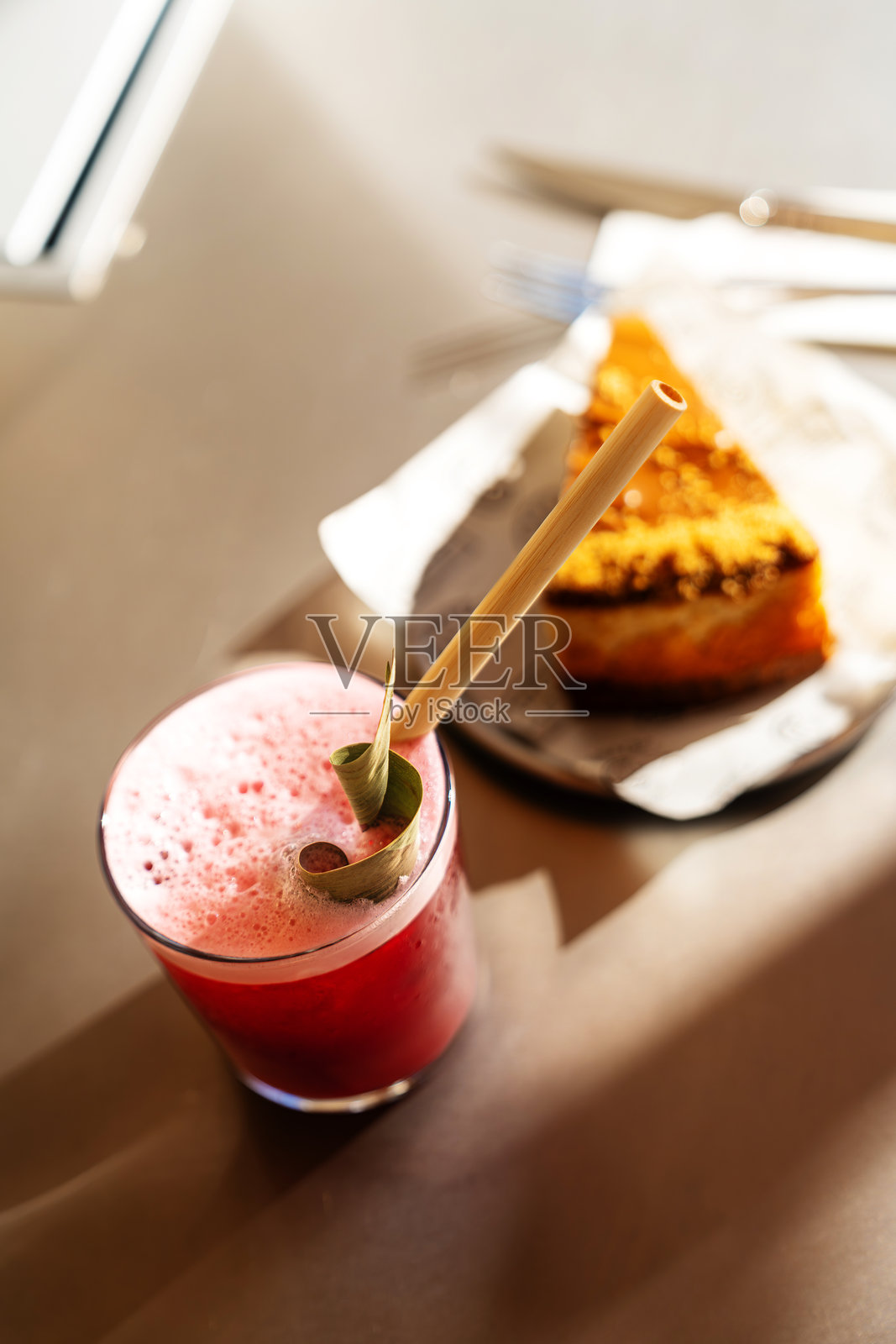 相机聚焦在桌子上的一杯新鲜果汁和一片蛋糕上。照片摄影图片