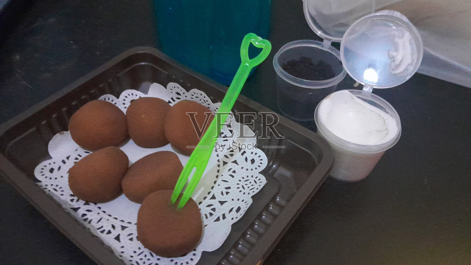 裹着可可粉和糯米粉的麻糬小球,旁边有奶酪酱和奥利奥粉作为蘸料。照片摄影图片