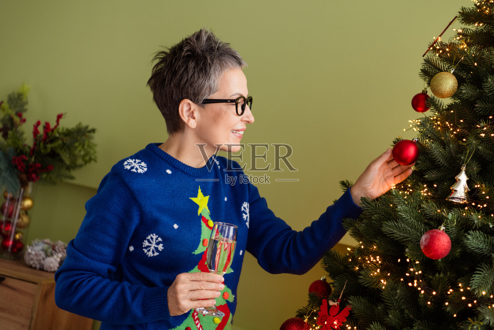 可爱的女孩穿着蓝色毛衣,手持圣诞树装饰品,室内庆祝圣诞和新年。照片摄影图片