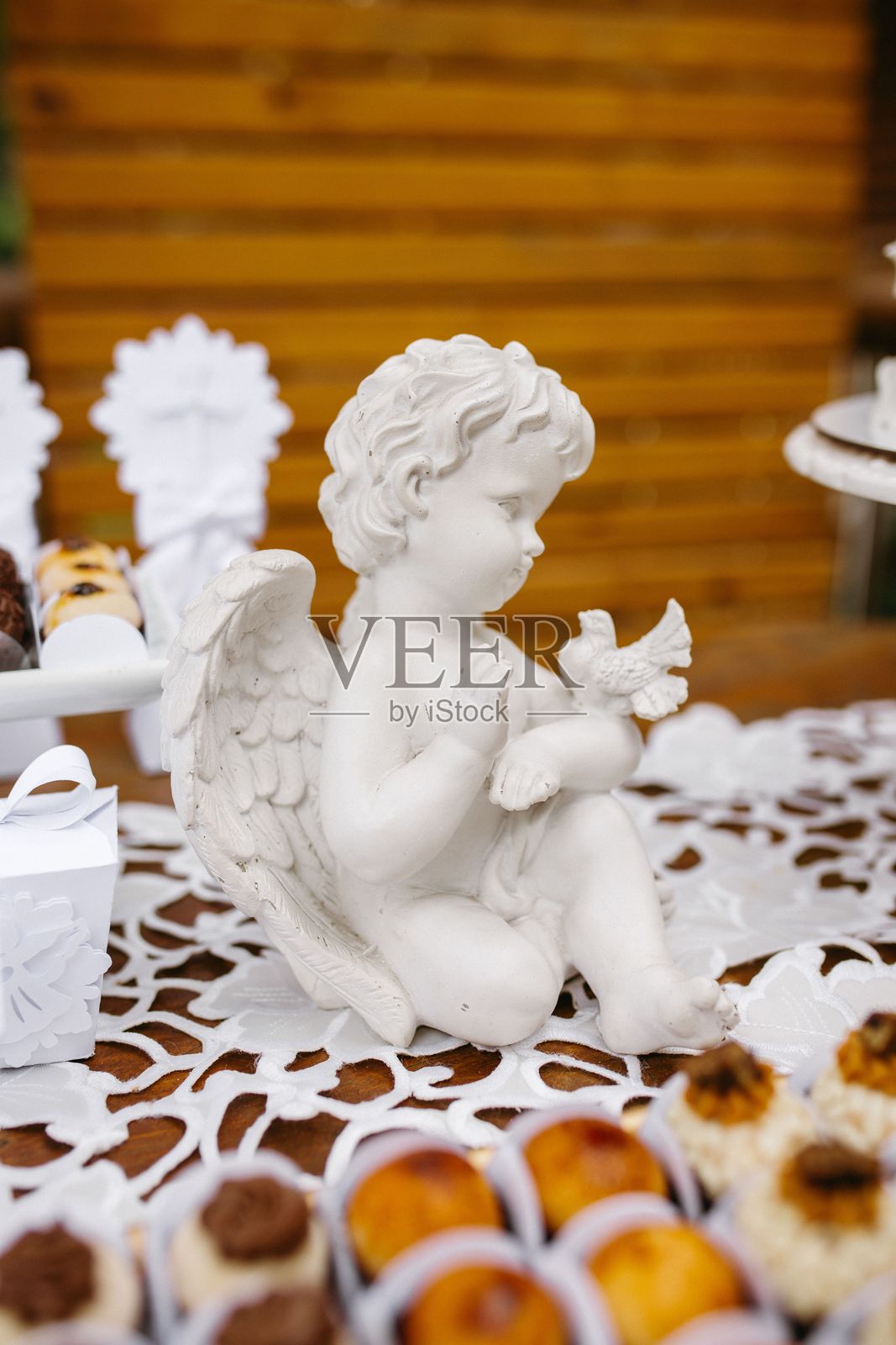 装饰性的天使雕像与蕾丝桌布上的糕点。照片摄影图片