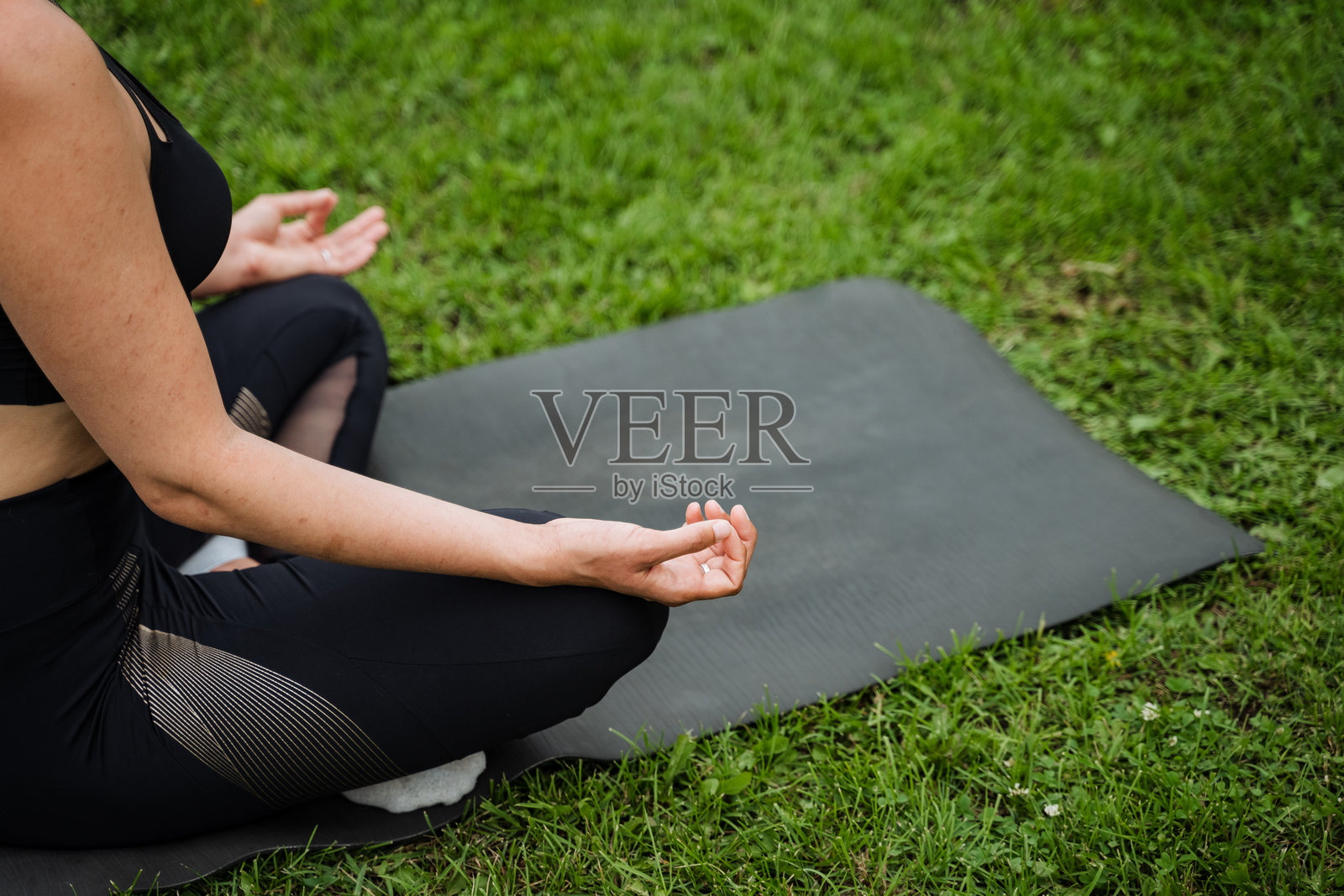 一位女性沉浸在宁静的户外环境中,冥想于瑜伽垫上,寻找内心的平静与和谐,培养正念与整体健康。照片摄影图片