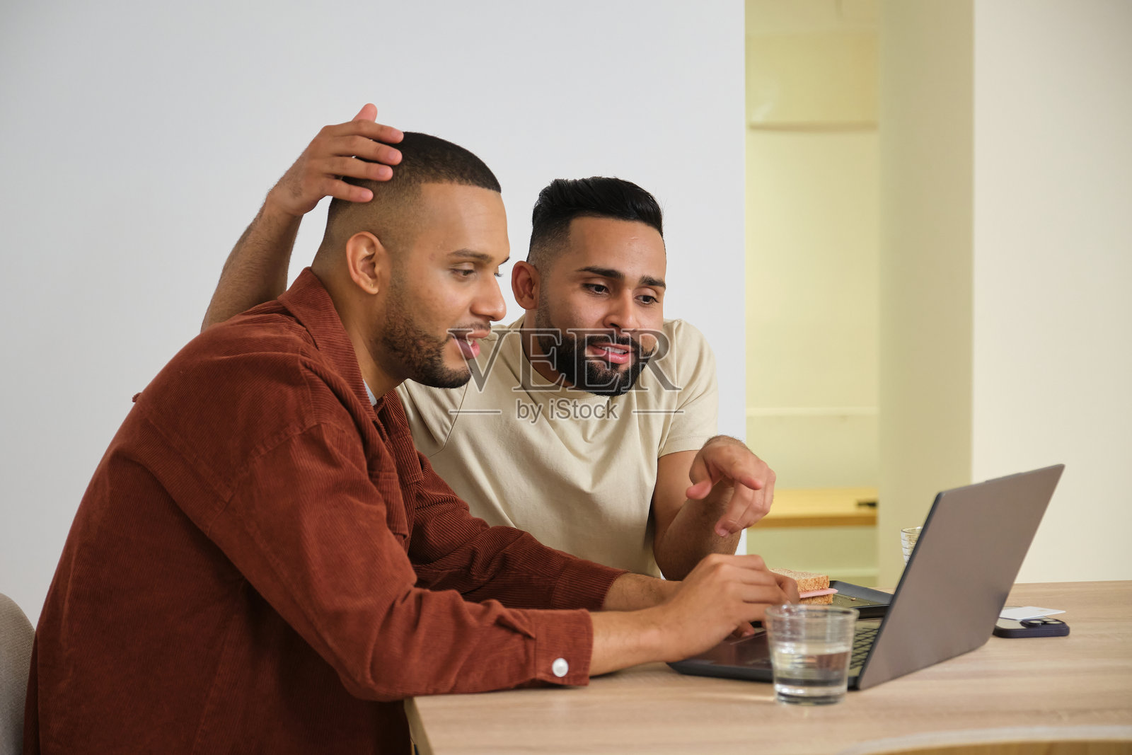 两个男性朋友在家里愉快地一起使用笔记本电脑。照片摄影图片