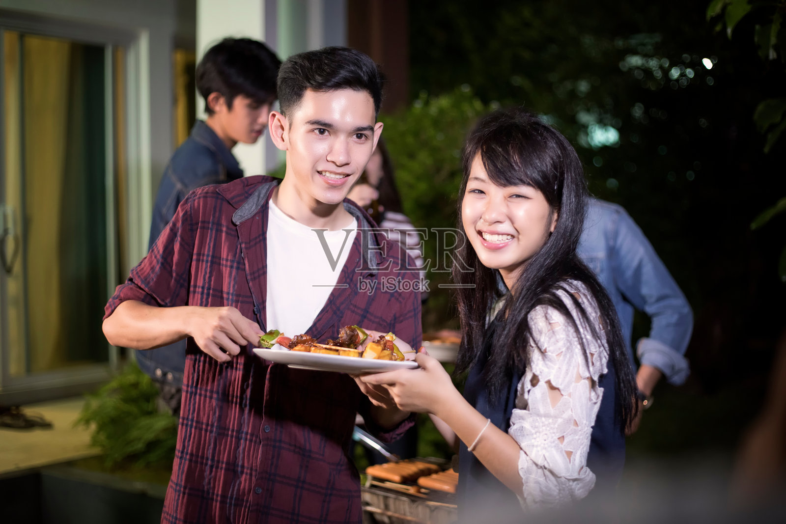 微笑的朋友晚上在后院吃饭照片摄影图片