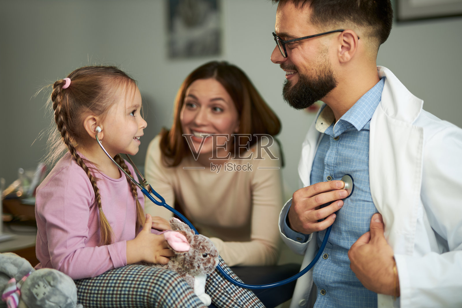 快乐的女孩用听诊器听医生的心跳照片摄影图片
