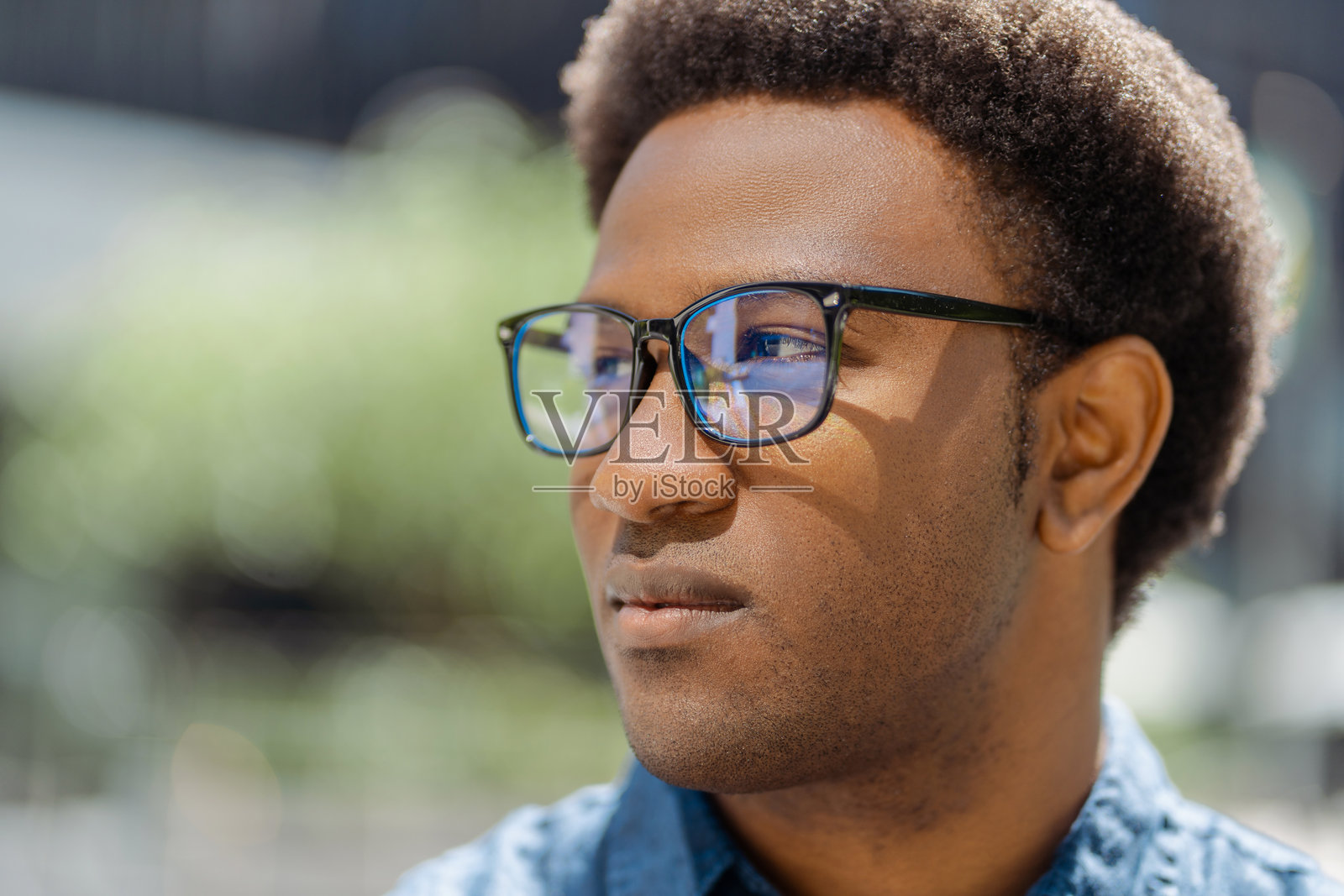 年轻男子戴着眼镜,侧目沉思。照片摄影图片