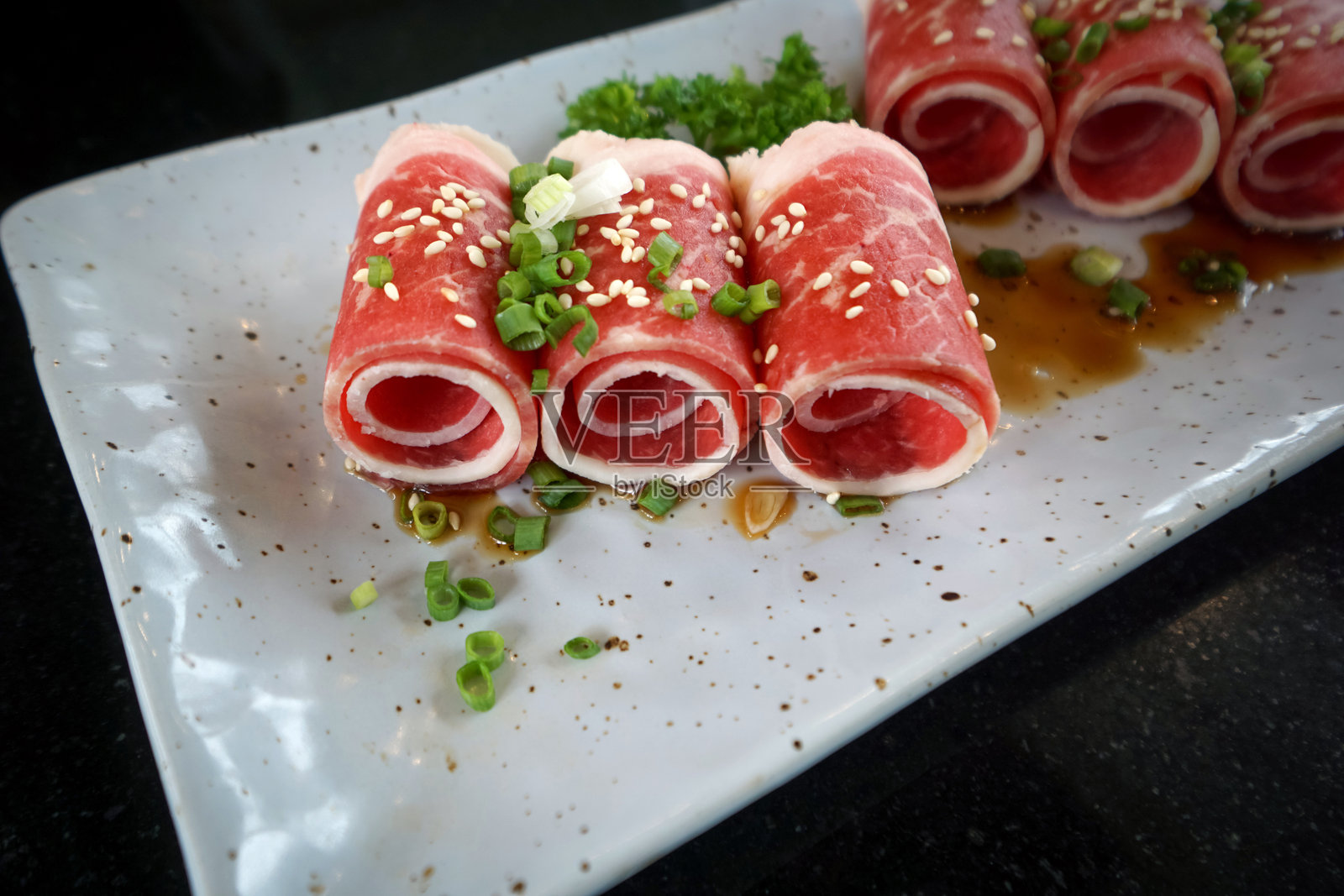 优质鹿儿岛黑猪肩肉片,配有酱汁和切碎的葱,盛放在陶瓷盘中。照片摄影图片