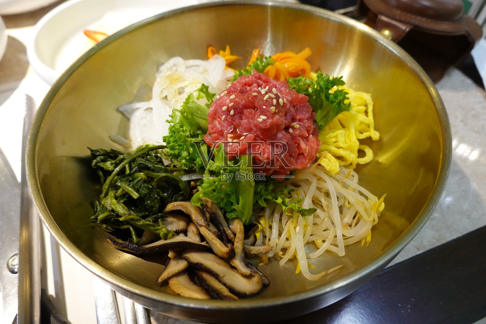 生鱼片拌饭是一道韩国美食,包含新鲜蔬菜、米饭和调味生牛肉(生鱼片),上面放有生蛋黄和辣椒酱。这道菜每一口都带来独特的风味和口感。照片摄影图片