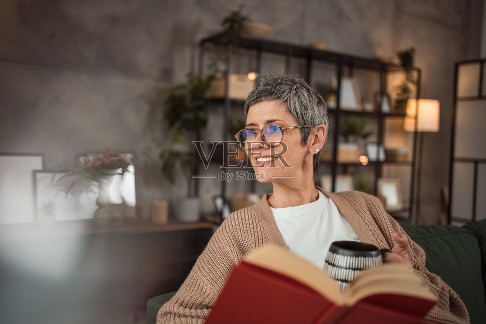 一个成熟的女人在她舒适的公寓里坐在客厅里,沉迷于她最喜欢的书照片摄影图片