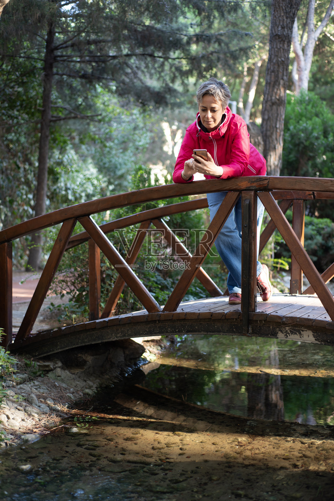 女人在美丽的公园里度过时光,用手机拍照照片摄影图片