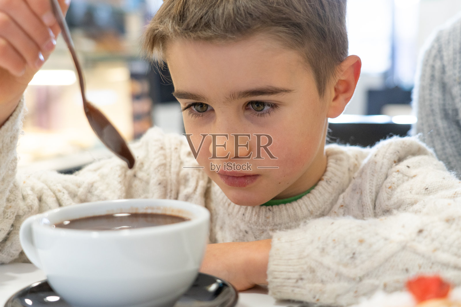 白人男孩在冬季的咖啡馆里喝热巧克力照片摄影图片