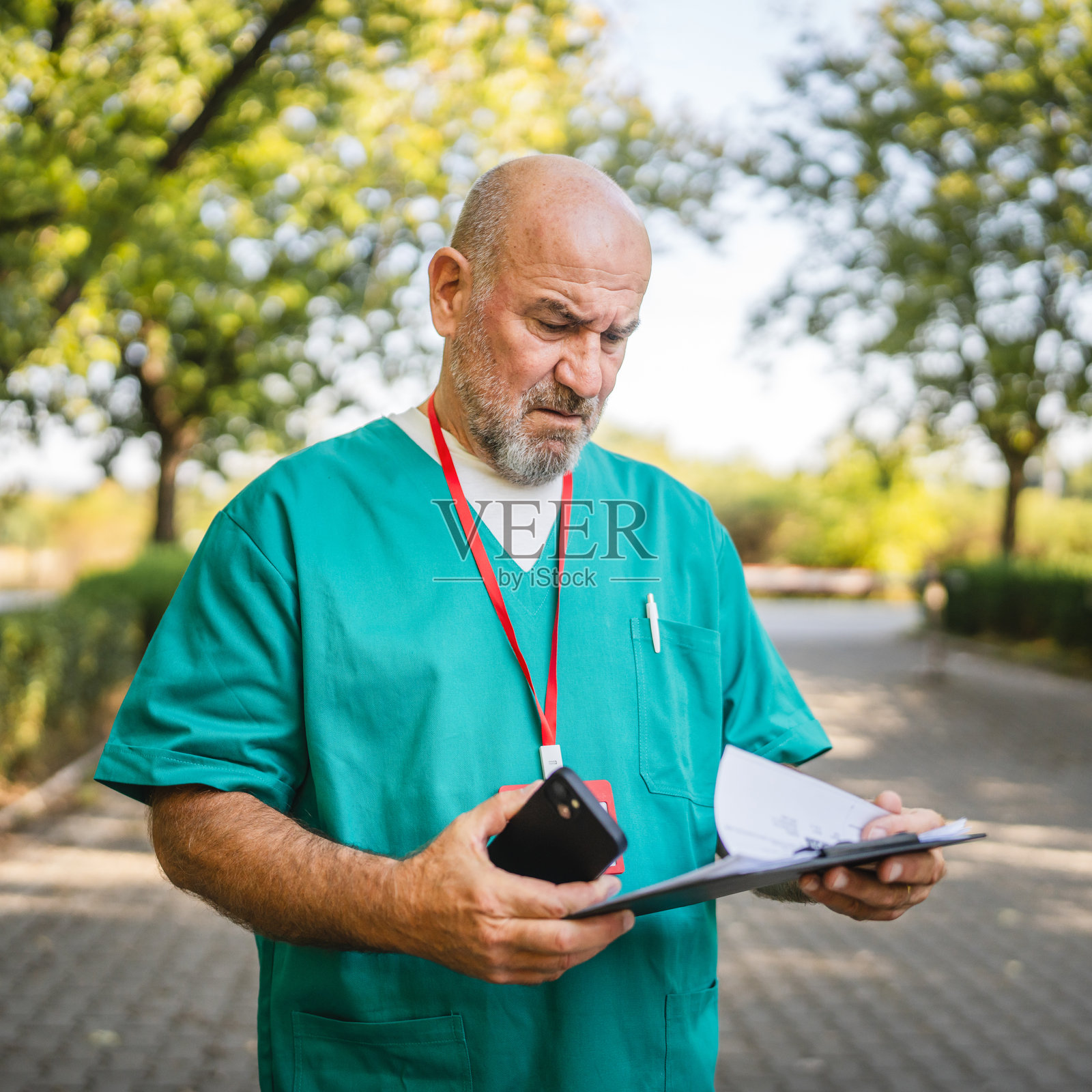 的老年男性医生在户外阅读夹板上的文件照片摄影图片