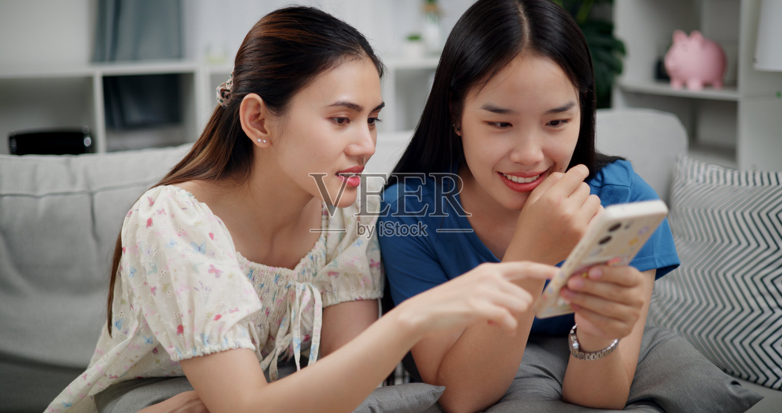 两个兄弟姐妹正在一起用手机观看搞笑视频片段。照片摄影图片