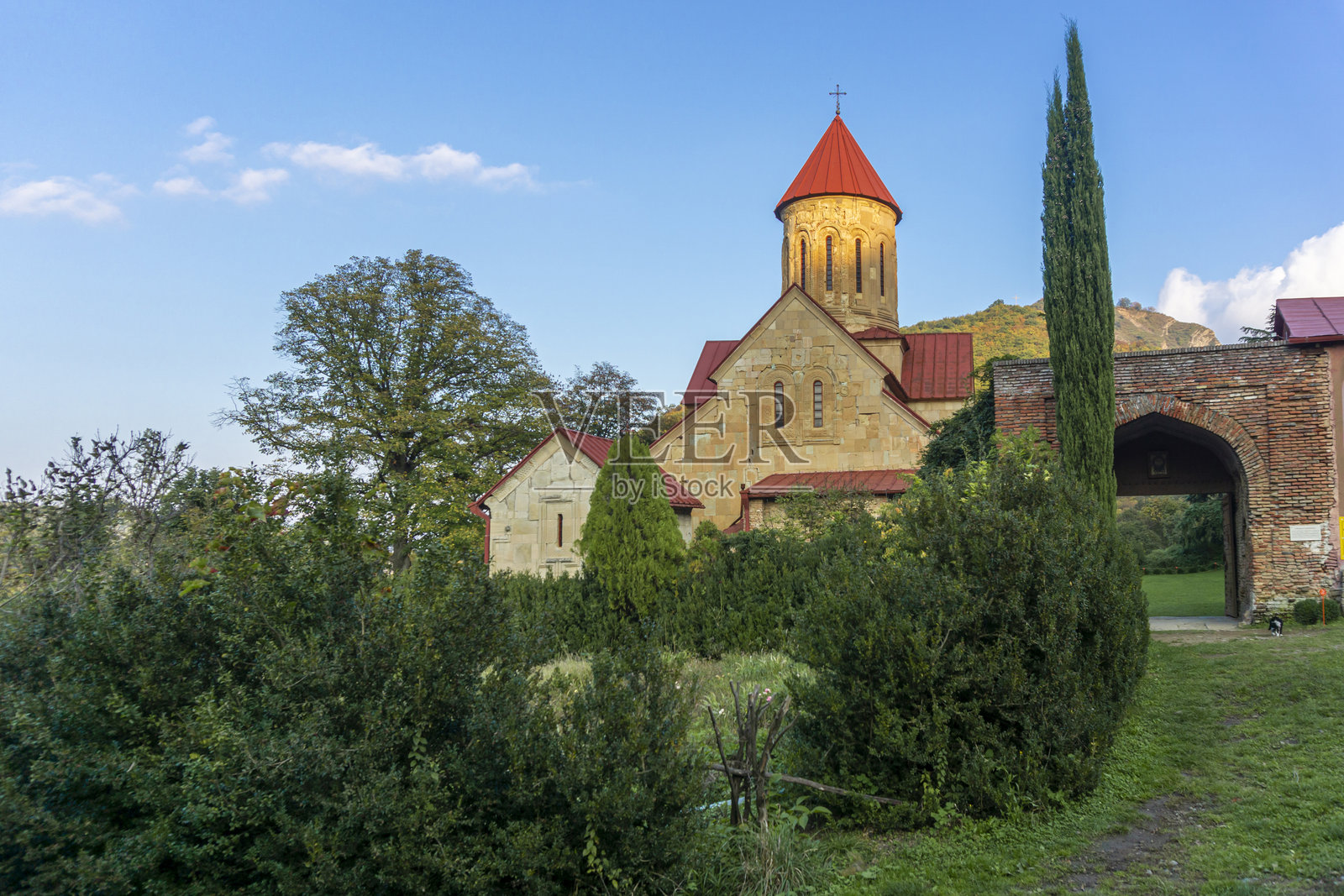 贝塔尼亚修道院的主入口。主教堂在落日的余晖中。高大的柏树。背景是山丘和天空。照片摄影图片