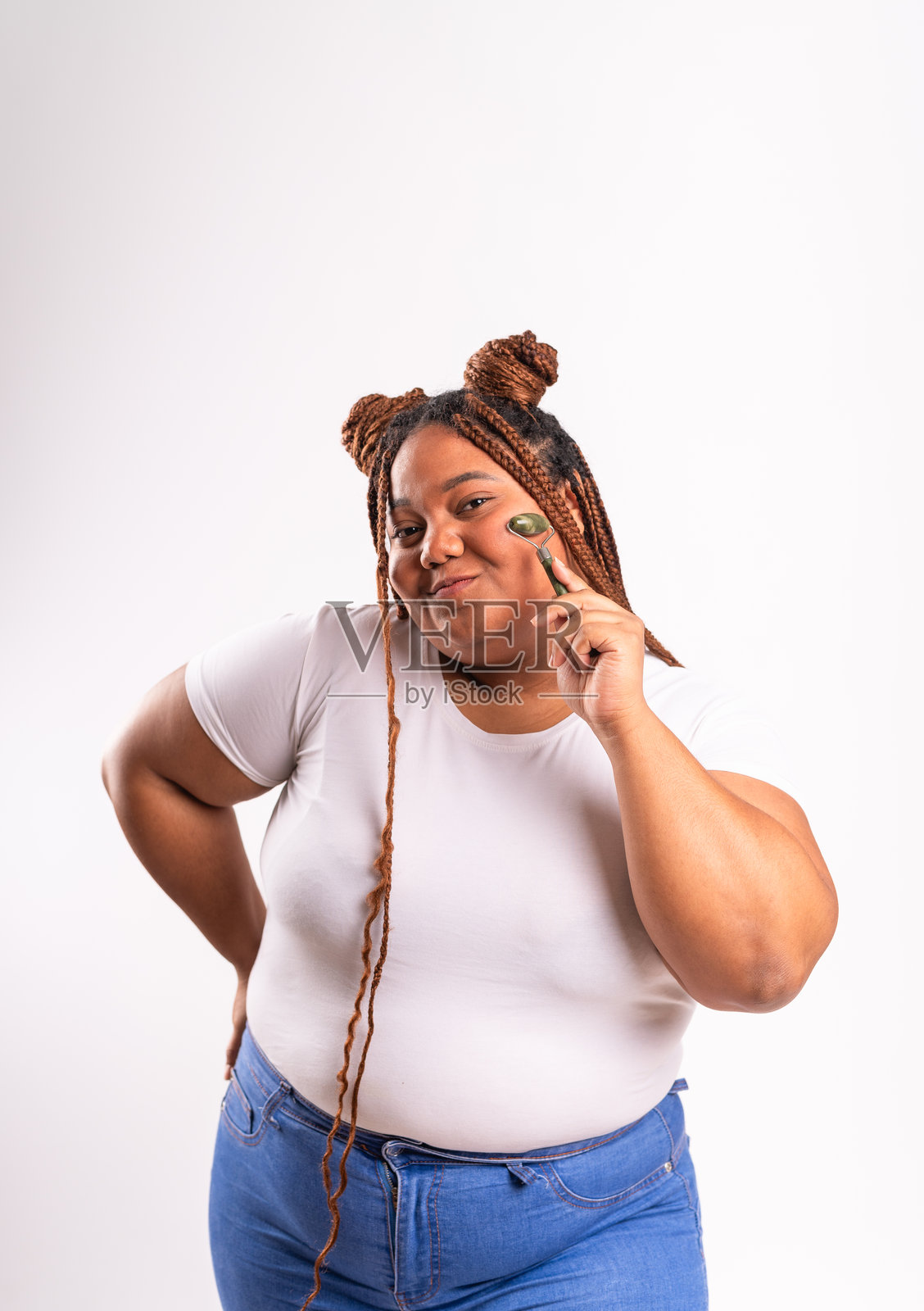 一位胖胖的黑人女性正在使用玉石滚轮按摩面部肌肤照片摄影图片