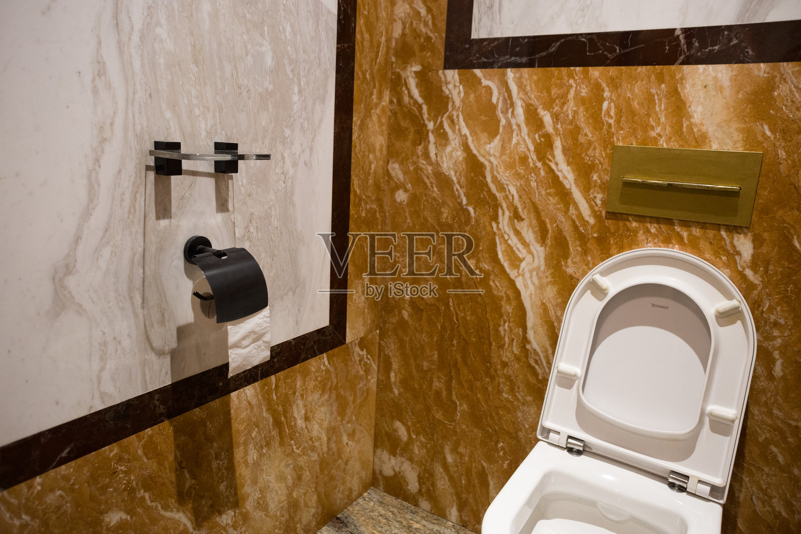 一个白色马桶位于墙壁上有时尚瓷砖的房间里。餐厅里的马桶。照片摄影图片