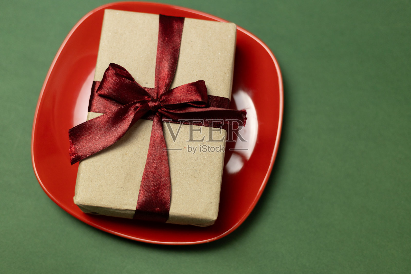 红盘子上的礼品盒,系着丝带照片摄影图片