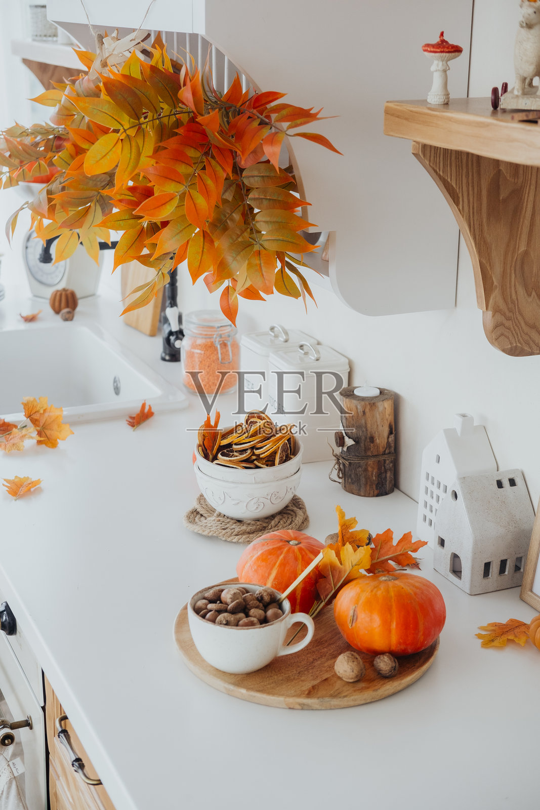 温馨的秋季厨房装饰,木质台面上摆放着南瓜和五彩斑斓的树叶照片摄影图片