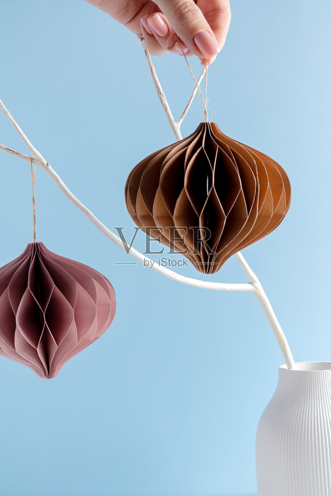 现代环保圣诞室内装饰。斯堪的纳维亚风格的圣诞纸蜂巢挂在干枝上,背景为蓝色。照片摄影图片