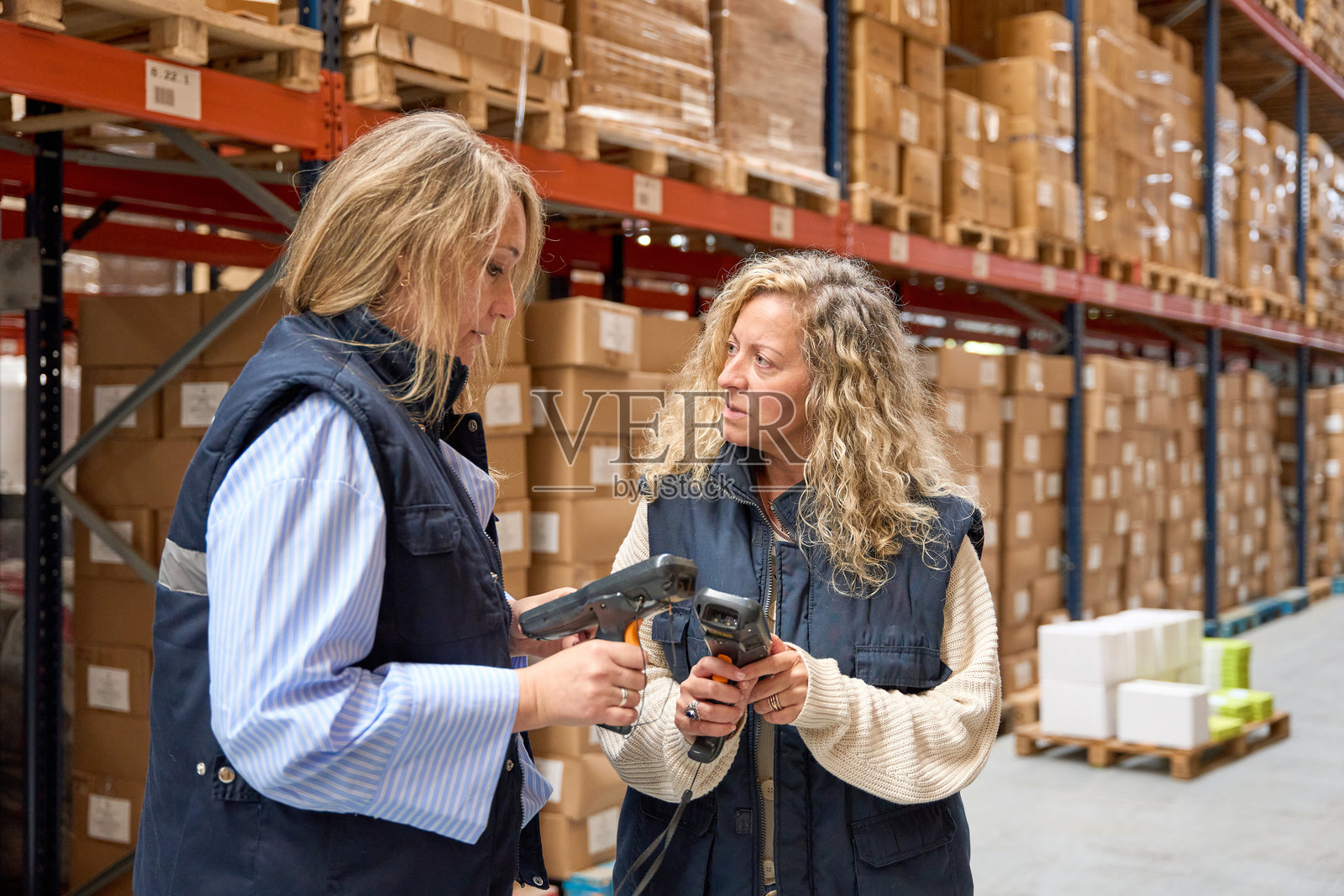 女性仓库工人在物流中心讨论使用条形码扫描器照片摄影图片