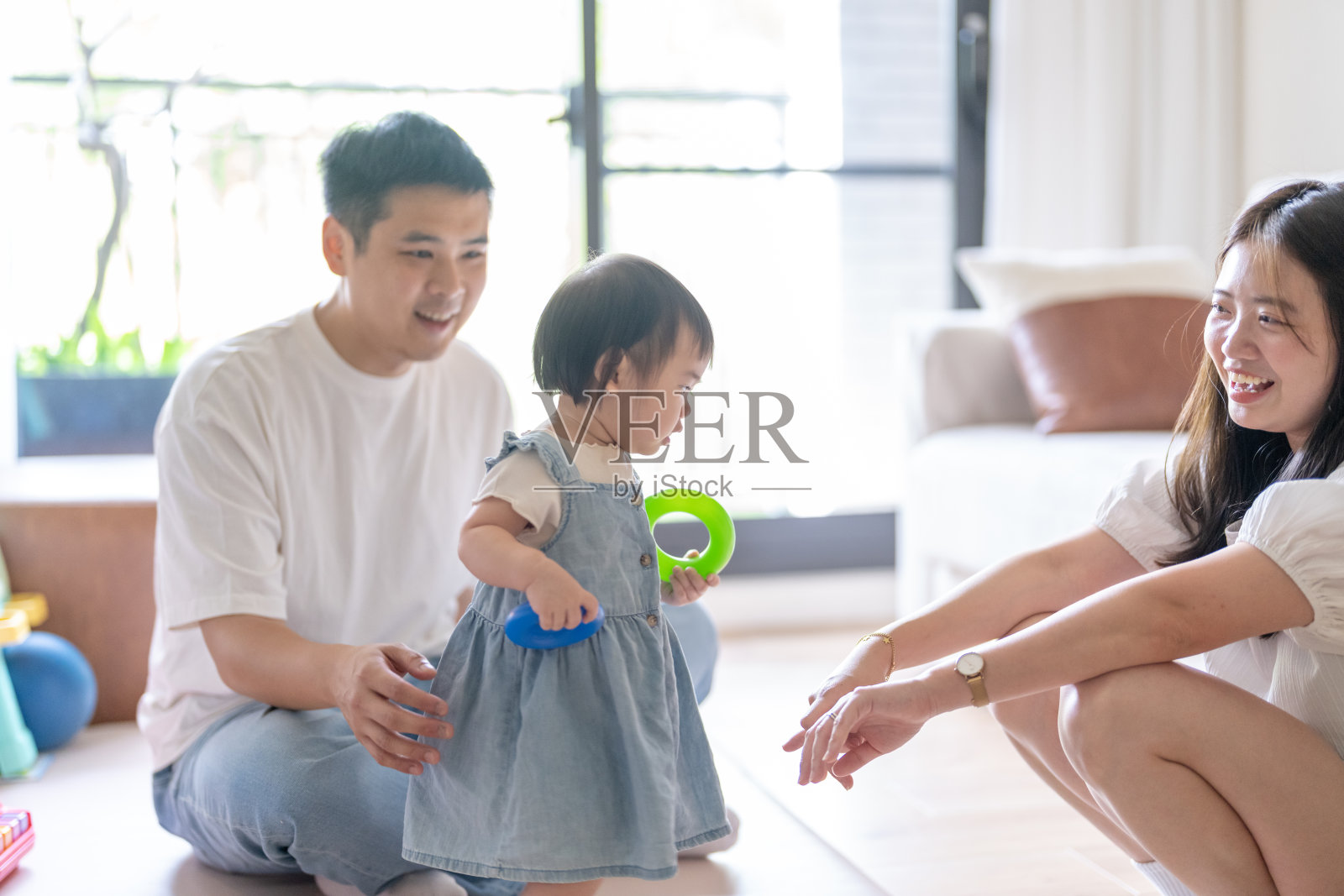 一名1岁的台湾女孩在台中市一栋高层公寓的房间里,和她的父母(20多岁的男女)快乐地玩耍。照片摄影图片