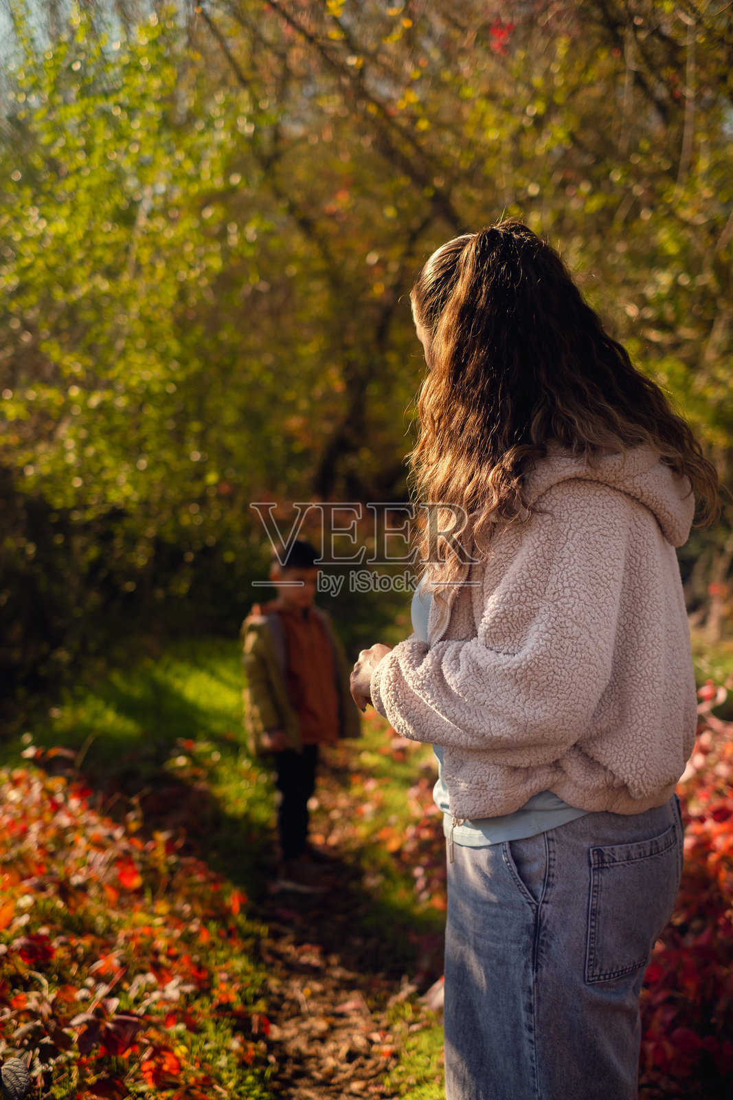母亲和儿子在秋季森林中采集蘑菇,享受着收集草药和浆果的家庭时光——一种环保的爱好。照片摄影图片