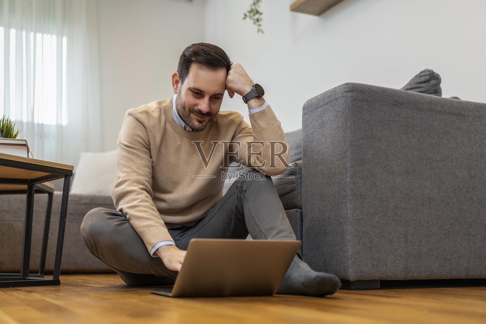 微笑的男人在舒适的客厅里使用笔记本电脑工作照片摄影图片