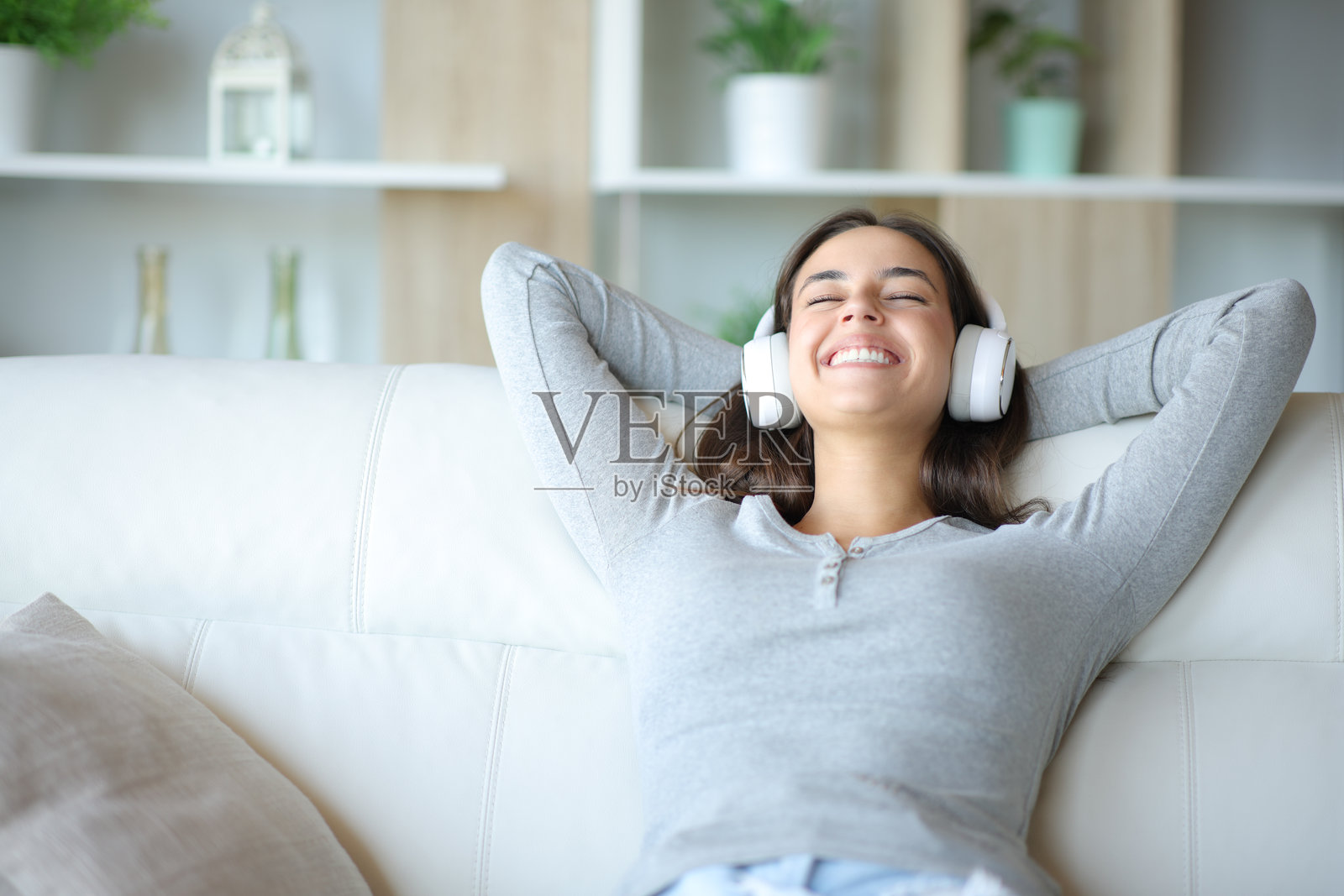 快乐的女人在家中戴着耳机听音乐,放松休息。照片摄影图片