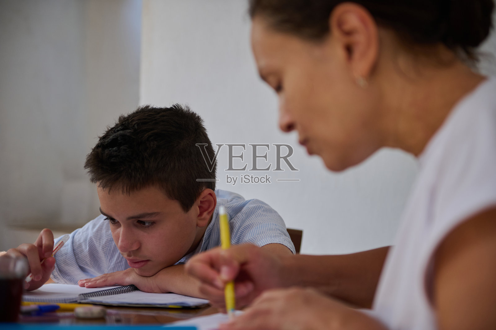 母亲在餐桌上帮助儿子做作业照片摄影图片