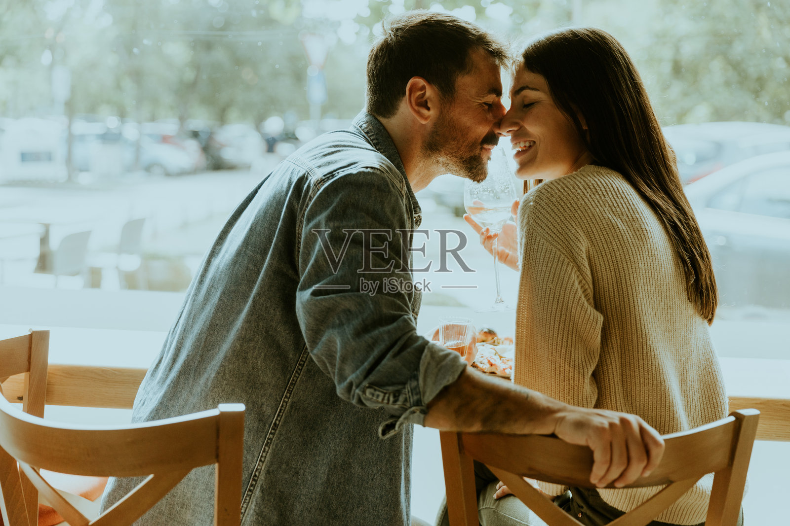 一对情侣在城市中心的阳光明媚的咖啡馆里享受甜点,共度温暖的下午时光。照片摄影图片