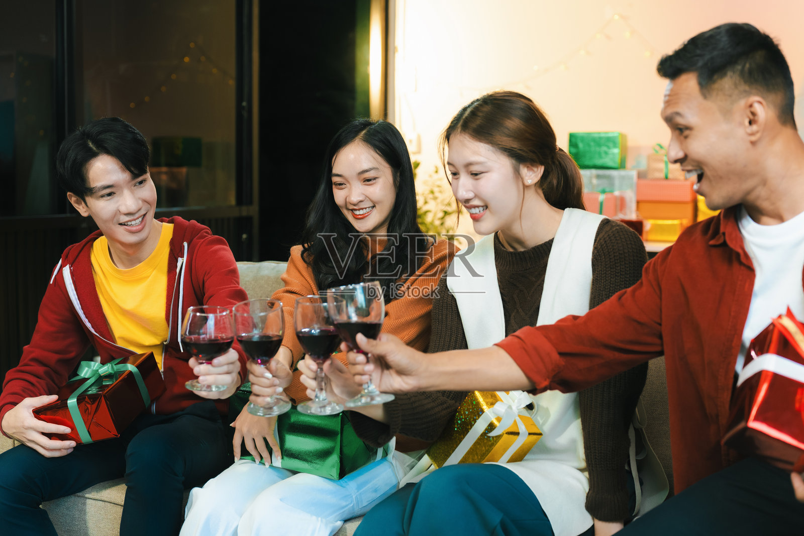 饮品与交谈,年轻人的新年社交聚会,活动中的团体与礼物交换,家庭庆祝活动。照片摄影图片