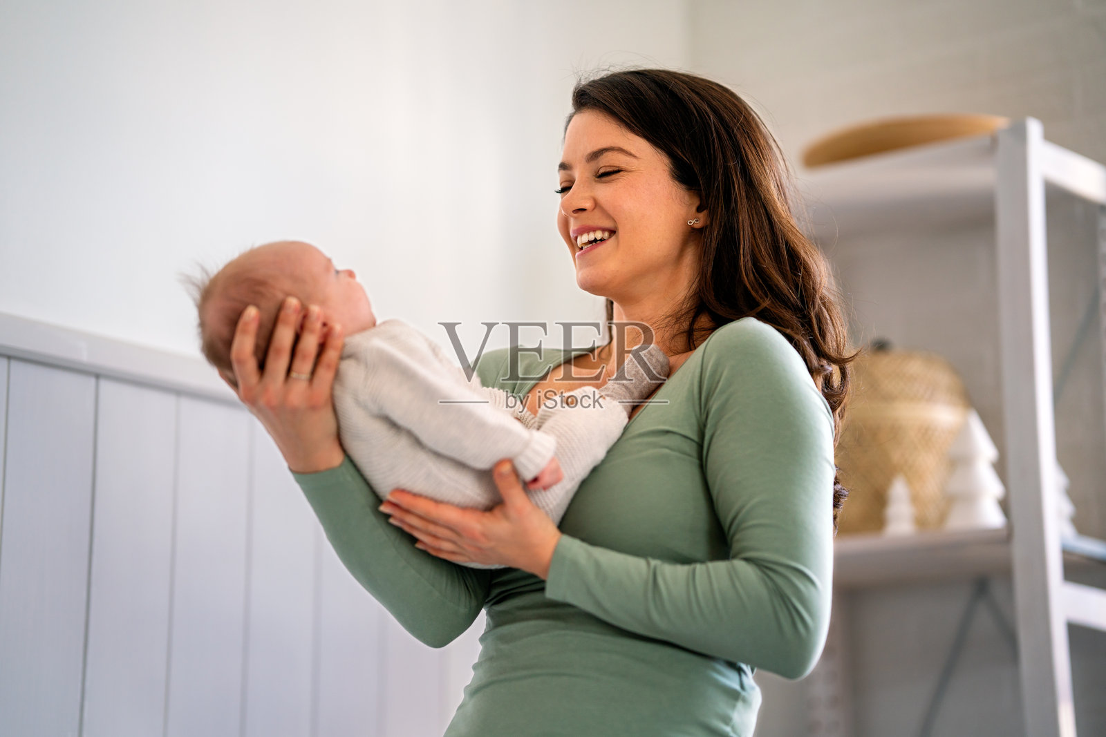 充满爱的单身母亲在家中抱着她的新生儿。人们热爱关心家庭的理念。照片摄影图片