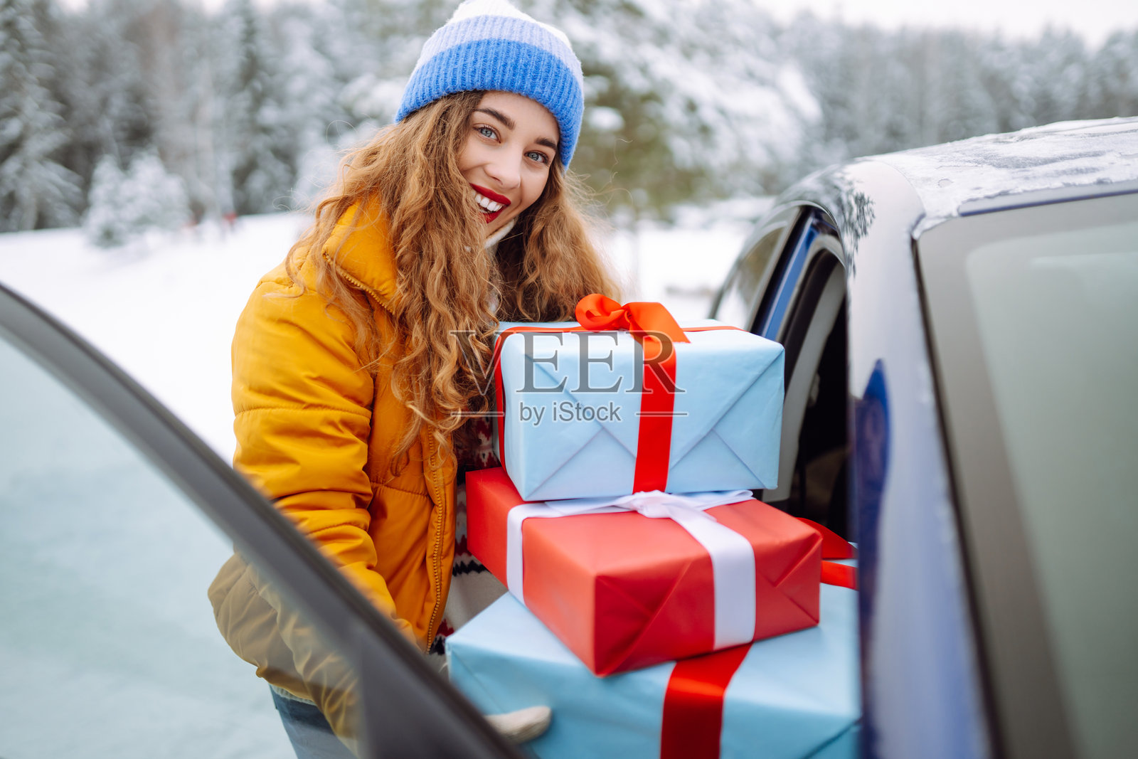 快乐的女人把新年礼物放进车里。照片摄影图片