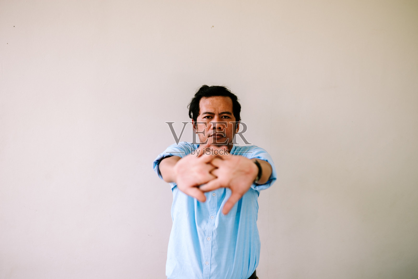 一位东南亚男子双手交叉,掌心向前翻转。照片摄影图片