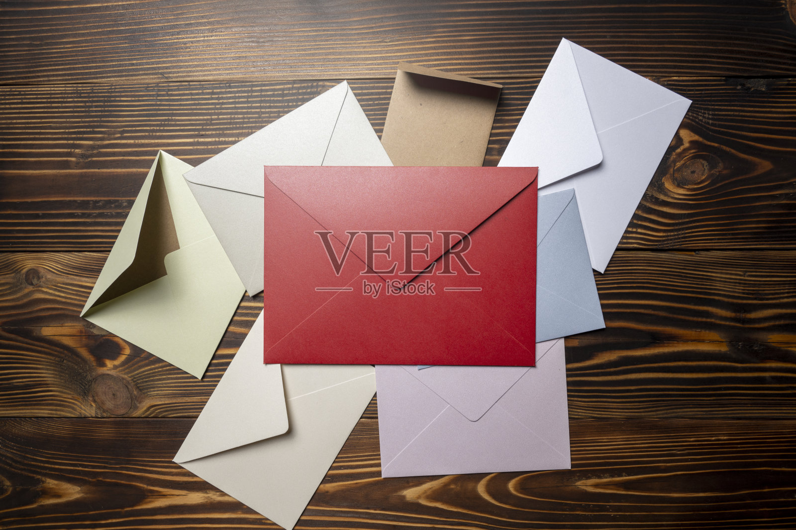 从上方俯视木质背景上的信封和明信片堆叠。信封的尺寸和颜色各不相同。照片摄影图片