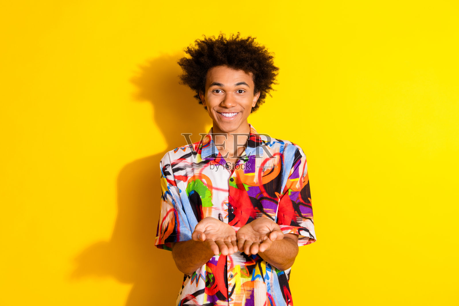 年轻男子穿着衬衫,手持展示空白空间,背景为明亮的黄色。照片摄影图片