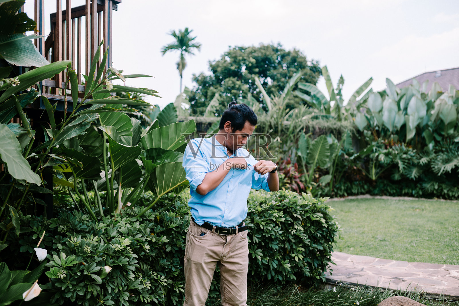 一位东南亚男子正在检查他的衬衫口袋,微微向前倾身仔细查看。照片摄影图片